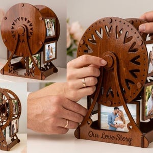 Peut inclure: Un cadre photo en bois brun foncé en forme de grande roue avec plusieurs emplacements rectangulaires pour afficher des photos. La base de la structure porte l'inscription gravée Our Love Story. Le design inclut des découpes en forme de cœur.