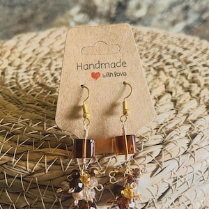 Pendientes colgantes cúbicos marrones con pequeñas cuentas de vidrio.