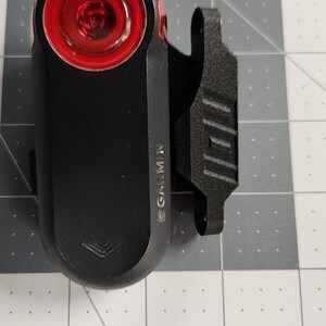 Pode incluir: Luz traseira de bicicleta Garmin preta com lente vermelha brilhante. A luz tem um corpo retangular e um clipe para fixa&ccedil;&atilde;o. O logotipo da Garmin &eacute; vis&iacute;vel na lateral. Projetado para seguran&ccedil;a e visibilidade ao andar de bicicleta.