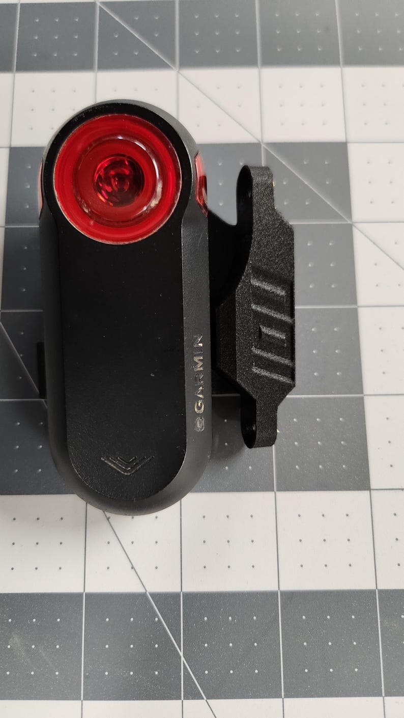 Pode incluir: Luz traseira de bicicleta Garmin preta com lente vermelha brilhante. A luz tem um corpo retangular e um clipe para fixa&ccedil;&atilde;o. O logotipo da Garmin &eacute; vis&iacute;vel na lateral. Projetado para seguran&ccedil;a e visibilidade ao andar de bicicleta.