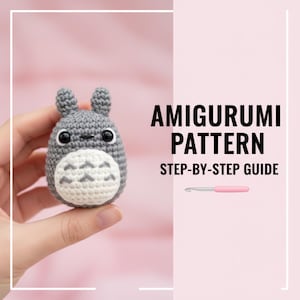 Puede incluir: Una figura amigurumi gris tejida a ganchillo de un personaje de dibujos animados, sostenida en una mano. La figura tiene una barriga blanca y ojos negros. El texto a la derecha dice "AMIGURUMI PATTERN STEP-BY-STEP GUIDE". También se muestra un ganchillo rosa.