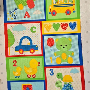 May include: A rectangular fabric panel featuring a colourful patchwork design with illustrations of a green aeroplane, a yellow school bus, a blue car, a green teddy bear with a red balloon, and three stacked turtles, alongside letters and numbers.