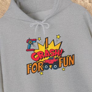 Peut inclure: Un sweat à capuche gris clair avec un motif « I CRASH FOR FUN ». Le motif comprend une télécommande rouge, un monster truck rouge, des étoiles jaunes et un fond en forme d'explosion jaune.