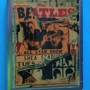 May include: A rectangular box featuring a collage of The Beatles imagery, including text reading The Beatles, All Star Show, and Shea Stadium. The design incorporates layered, torn-paper effects with black and white portraits and band members playing guitars, all encased in a silver-toned frame.