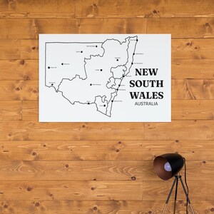 May include: A white rectangular wall art print featuring a black outline map of New South Wales, Australia. The map includes black dots marking various cities and towns, with the text NEW SOUTH WALES AUSTRALIA printed in bold black lettering.
