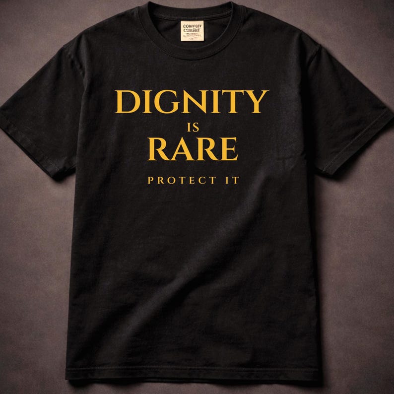 May include: Black t-shirt with the words "DIGNITY IS RARE PROTECT IT" printed in gold. The shirt has a crew neck and short sleeves. The shirt is made of a soft material.