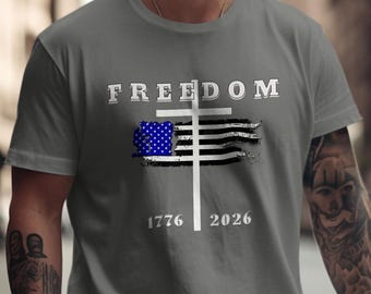 Comfort Colors®, T-shirt con croce della libertà, bandiera americana effetto invecchiato, maglietta con scritta "Credenza cristiana", abbigliamento patriottico con design 1776-2026.