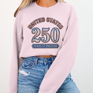 Light pink sweatshirt with "United States 250 Years of Freedom" text and mosaic design.