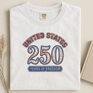 White t-shirt with "United States 250 Years of Freedom" graphic.