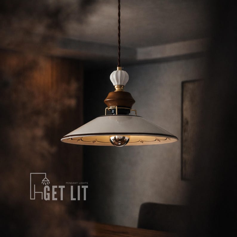 May include: A pendant light fixture with a white, downward-facing shade, trimmed with a black border and gold accents. The fixture has a brown and white decorative top and a brown cord. The text "GET LIT" is in the lower left corner.