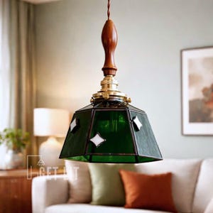 May include: A green glass pendant light with a geometric shade, featuring white diamond accents. The light fixture has a wooden top and brass hardware. The lamp hangs from a brown cord, adding a vintage touch to the room.