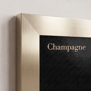 May include: A rectangular wall art piece featuring a brushed champagne gold metal frame surrounding a solid black background. The word Champagne is printed in a light gold serif font in the upper portion of the black rectangular center area.