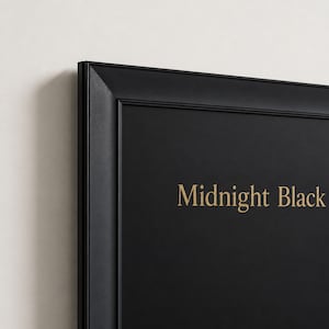 May include: A rectangular black frame with a matte finish surrounding a solid black surface. The text Midnight Black is printed in a gold serif font on the right side of the black surface. The frame features a beveled edge and a clean border.
