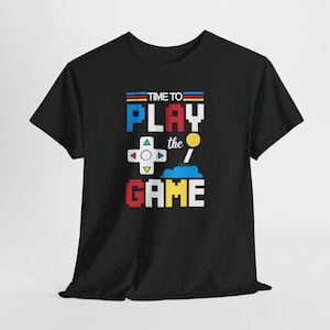 Puede incluir: Una taza de cerámica blanca con asa negra y el texto "But First, Coffee" en negrita negra. La taza se encuentra sobre un fondo borroso, sugiriendo un ambiente acogedor.