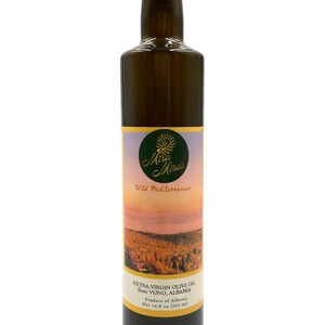 May include: A dark glass bottle of Mira Mira's Extra Virgin Olive Oil from Vuno, Albania. The label features a sunset landscape and the text "Wild Mediterranean." The bottle contains 16.9 fl oz (500 ml) of olive oil.