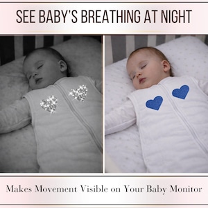 May include: A baby wearing a white sleep sack with a blue heart design. The sleep sack has a zipper down the front. The text at the top says "SEE BABY'S BREATHING AT NIGHT". The text at the bottom says "Makes Movement Visible on Your Baby Monitor".