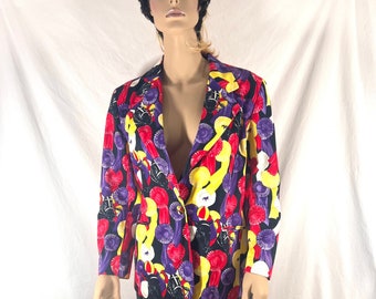 May include: A black blazer with a colorful print of red, yellow, purple, and white ribbons. The blazer has a button closure and long sleeves. The model is also wearing a black skirt with a gray and black pattern.