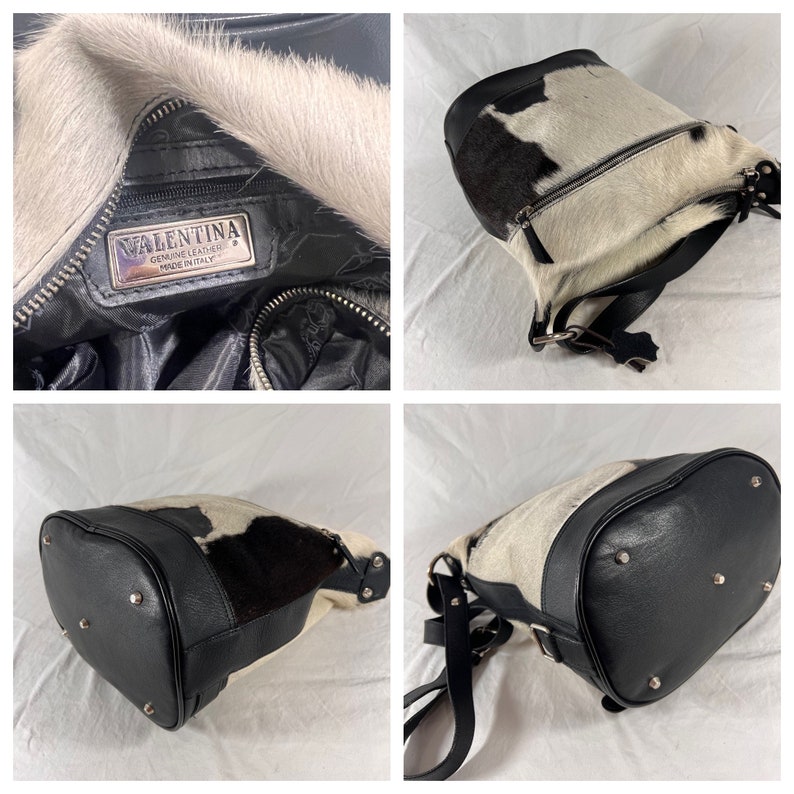 Puede incluir: Bolso de cuero negro de estilo cubo con un patr&oacute;n de piel de vaca blanca y negra. El bolso tiene cierre de cremallera y una etiqueta de metal plateado que dice "Valentina Genuine Leather Made in Italy".
