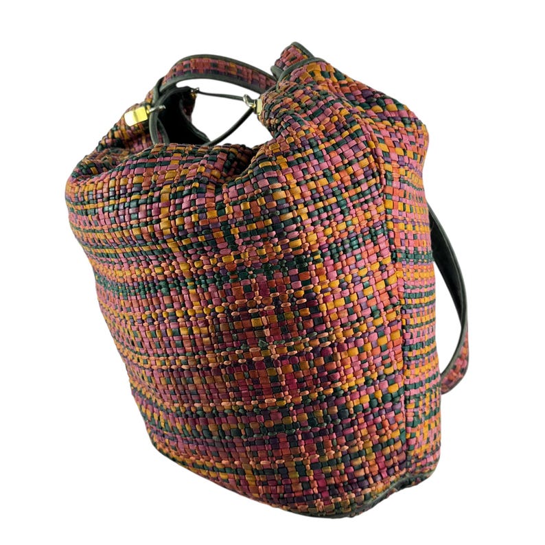 May include: A woven bucket bag in a mix of colours including pink, orange, green, and burgundy. The bag has a black handle and strap. The woven material gives the bag a textured appearance. The bag is designed to be carried over the shoulder.