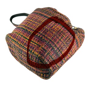May include: A multi-coloured woven tote bag with a black handle and trim. The bag features a tight weave pattern with shades of pink, orange, yellow, and green. The bag appears to be well-made.