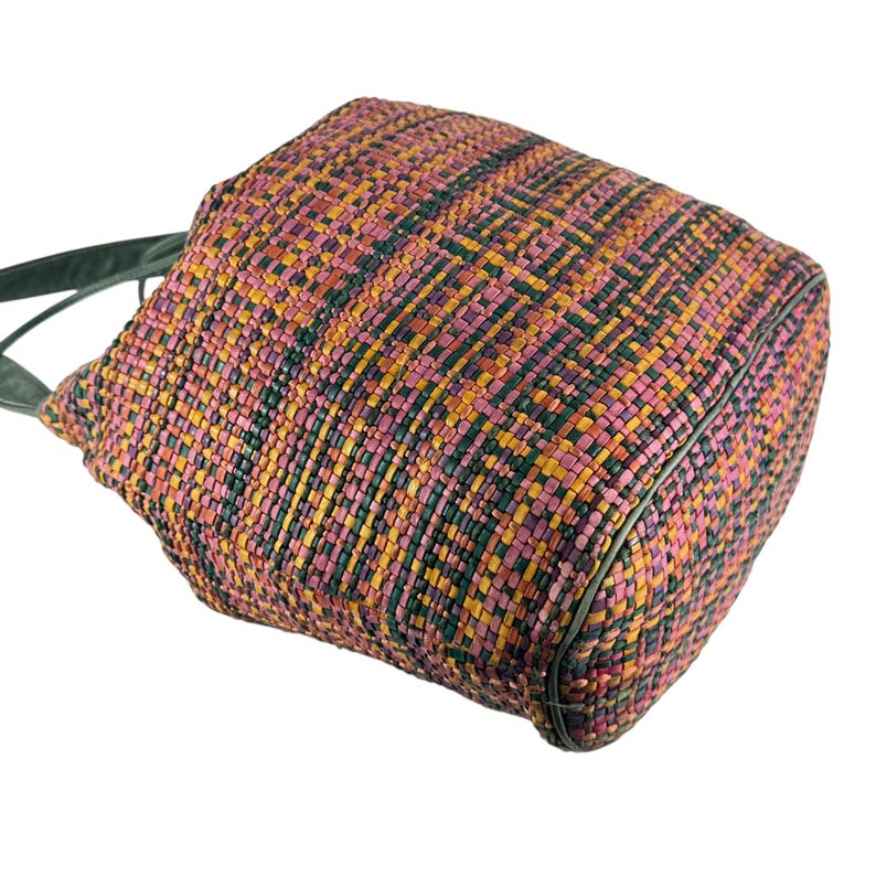 May include: A colourful woven tote bag featuring a pattern of pink, yellow, and green. The bag has a rectangular shape with dark green trim and handles. The weave is tight, suggesting a sturdy construction.