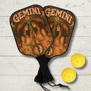 May include: Two pickleball paddles with a Gemini zodiac design. The paddles feature a vintage illustration of women, flowers, and celestial elements. They have black handles and are paired with two yellow pickleballs.