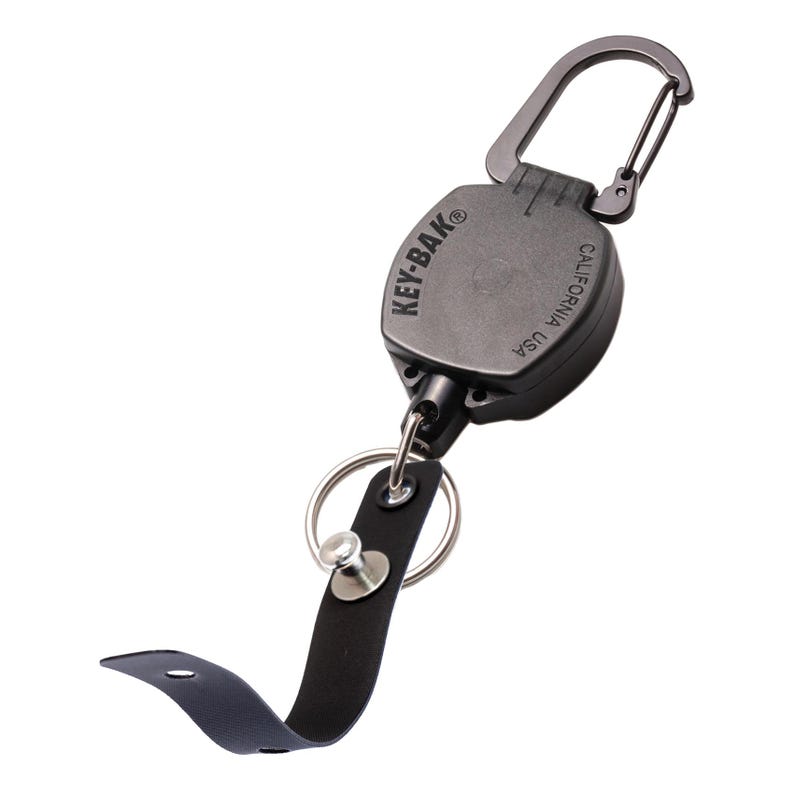 May include: A black KEY-BAK retractable key holder with a carabiner clip. The key holder has a black leather strap and a split ring for attaching keys. The text "KEY-BAK CALIFORNIA USA" is printed on the key holder.