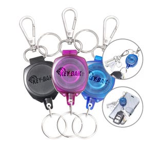May include: A collection of KEY-BAK retractable keychains in black, purple, and blue. Each keychain features a metal clip, a key ring, and a retractable cord. The KEY-BAK logo is visible on each keychain.