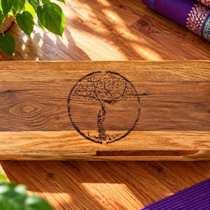 May include: A rectangular wooden block with rounded corners, featuring a dark brown wood grain pattern and a centred circular laser-engraved design of a tree. The surface is smooth and polished, showcasing natural wood textures and tones.