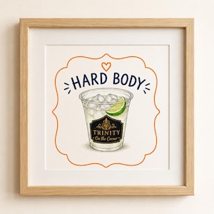 Op de afbeelding: Een ingelijste print met een cocktail in een doorzichtige plastic beker met ijs en een limoenpartje. De woorden "HARD BODY" staan boven de beker en het label luidt "TRINITY On the Corner". Het kunstwerk is omgeven door een oranje decoratieve rand.