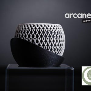 Könnte beinhalten: Ein moderner Pflanztopf mit geometrischem Design. Der weiße Topf mit Rautenmuster steht auf einem schwarzen, gebogenen Sockel. Das Wort "arcane" und das Wort "planter" sind in weißem Text oben rechts dargestellt.