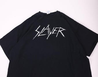 May include: Black t-shirt with the word "SLAYER" in white, stylized, jagged lettering across the chest. The shirt is a basic crew neck style and appears to be made of cotton.