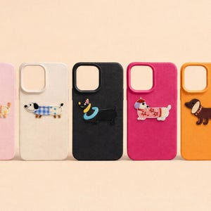 May include: Five colorful phone cases with dachshund dog designs. The cases are pink, white, black, magenta, and orange. Each case features a different dachshund design, with various outfits and accessories.