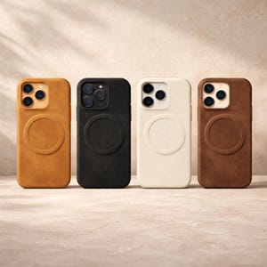 以下が含まれることがあります： 背面が円形デザインのスマートフォンケースが4つ並んでいます。ケースの色は、タン、黒、オフホワイト、茶色です。ケースは滑らかでマットな仕上がりで、スマートフォンにフィットするように設計されています。