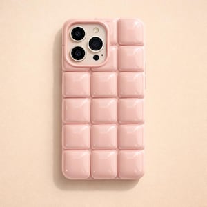 May include: A light pink phone case with a square, textured pattern. The case has a glossy finish and is designed to fit a smartphone with multiple camera lenses.