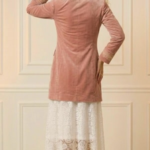 May include: A dusty rose velvet blazer with embroidered cuffs, paired with a white lace skirt. The outfit is completed with gold-colored high-heeled sandals. The ensemble is set against a neutral background.