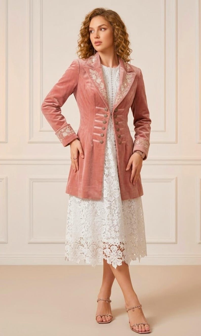 May include: A dusty rose velvet coat with ornate embroidery on the collar and cuffs. The coat features a row of decorative buttons and is worn over a white lace dress. The outfit is completed with strappy sandals.