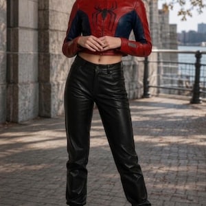 Puede incluir: Chaqueta de cuero roja y azul con un emblema de ara&ntilde;a negra en el pecho. La chaqueta se combina con pantalones de cuero negros y botas de combate negras. El atuendo se usa al aire libre.