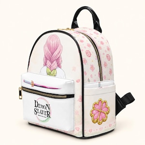 May include: A white backpack featuring a Demon Slayer graphic with a character with pink and green braided hair. The front pocket displays a sword and the Demon Slayer logo. The side has a pink flower emblem, and the bag is covered in a pattern of small pink flowers and hearts.