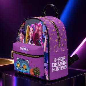 May include: A purple backpack featuring a graphic print of three animated characters on the front pocket, the text "HUNTRVX" above a cartoon cat, and "K-POP DEMON HUNTERS" on the side. The bag has gold-tone zippers and a repeating pattern of stars.