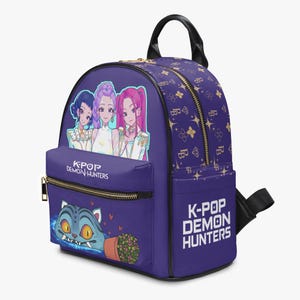 May include: Purple backpack with gold zippers and a top handle. The front features a cartoon of three anime-style women and a cat with the text "K-POP DEMON HUNTERS". The backpack has a repeating pattern of gold stars and the letter "B".