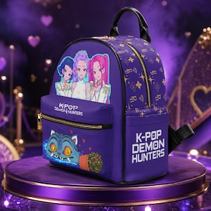 May include: A purple backpack featuring a graphic of three anime-style characters and the text K-POP DEMON HUNTERS. The front pocket displays a blue cat-like creature with yellow eyes and a potted plant. The bag has gold zippers and a repeating pattern.