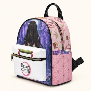 Könnte beinhalten: Ein Rucksack im Demon Slayer Design mit einer Vordertasche, die einen Bambus-Maulkorb und das Demon Slayer Logo zeigt. Das Hauptfach zeigt eine Figur mit langem schwarzem Haar in einem violetten Wald, ergänzt durch rosafarbene Seitenpaneele.