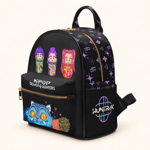 Puede incluir: Una mochila negra con el texto K-POP DEMON HUNTERS y HUNTRX. El frente muestra tres personajes de dibujos animados en tazas etiquetadas como Zoey, Rumi y Miar, además de una criatura azul con ojos naranjas y una pequeña planta en maceta.