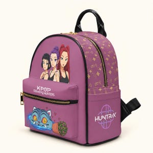 Könnte beinhalten: Ein violetter Rucksack mit einer Grafik von drei Anime-Figuren, dem Text K-POP DEMON HUNTERS, einer blauen katzenartigen Kreatur und einer Topfpflanze. Die Seite zeigt den Text HUNTRAX mit einem Logo und der Stoff hat ein goldenes Sternenmuster.