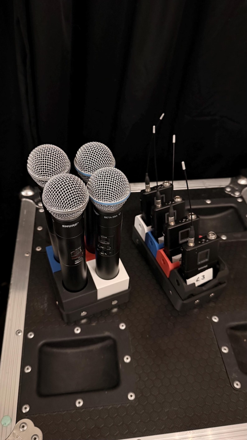 Puede incluir: Se muestran cuatro micr&oacute;fonos Shure Beta 58A con cabezales de malla plateada y cuerpos negros. Junto a ellos, varios receptores inal&aacute;mbricos negros con antenas. Los art&iacute;culos est&aacute;n sobre una superficie negra.