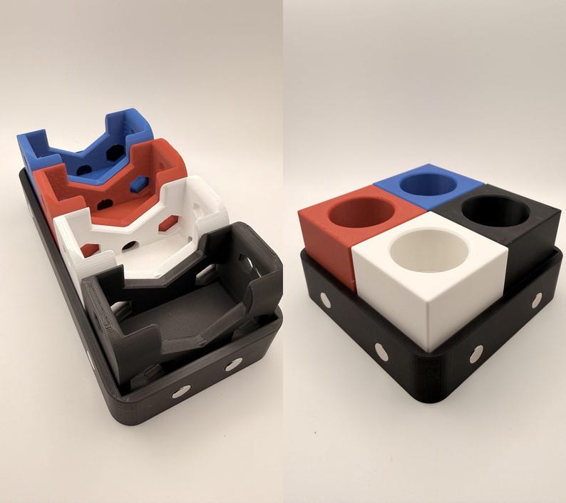 Puede incluir: Un conjunto de organizadores de escritorio multicolores de cuatro piezas, impresos en 3D. Los organizadores son rojos, blancos, azules y negros, y se asientan sobre una bandeja negra. La bandeja tiene detalles circulares blancos.