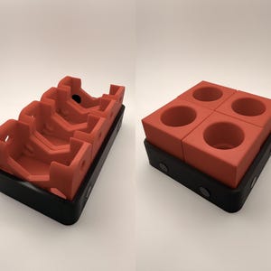 Puede incluir: Dos vistas de un juego de portavasos modular de color rojo anaranjado. Una muestra las piezas apiladas, la otra las muestra separadas. Los portavasos se asientan en una base negra con cierres magn&eacute;ticos. El juego est&aacute; dise&ntilde;ado para sostener cuatro tazas.