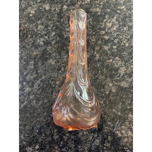 Op de afbeelding: Een vintage, lichtroze glazen vaas met een bolvormige basis en een slanke hals. De vaas heeft een textuur, wervelend ontwerp over de hele body. De basis is een donkerdere roze tint. De vaas is ongeveer 25 cm hoog.