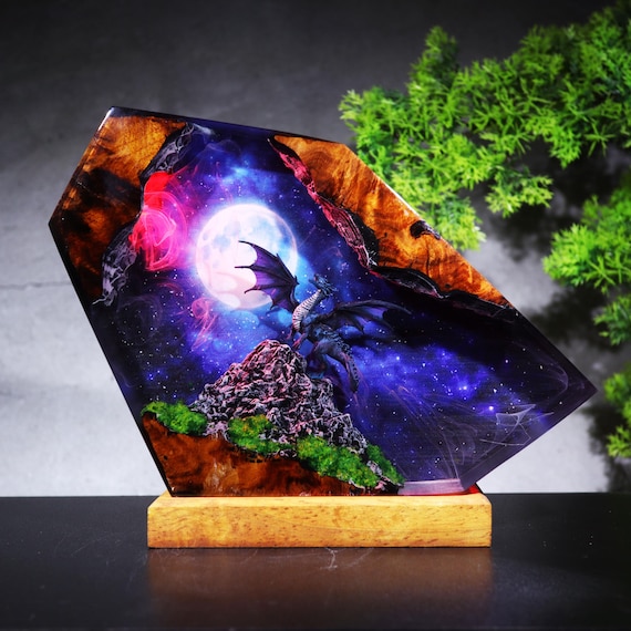 A hand-poured resin and wood diorama lamp featuring a gothic dragon in a galaxy moon scene — the kind of desk piece that stops visitors mid-sentence.